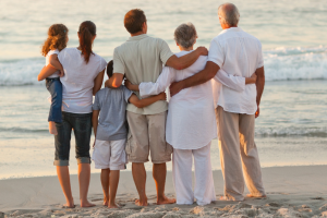 Backs of a family linking arms on the beach