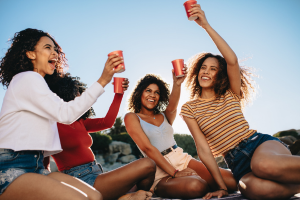 Four women raising their glasses for a toast on the beach